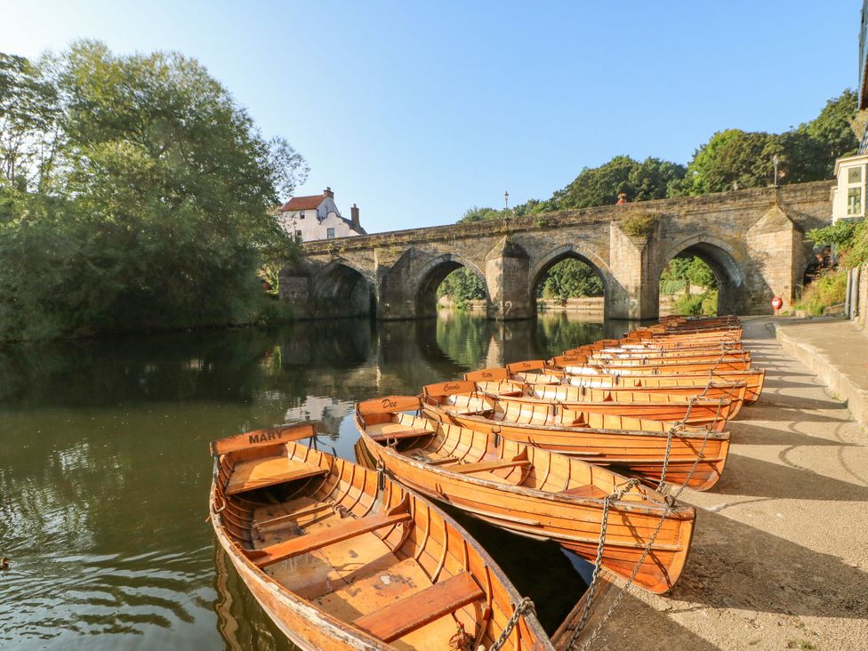 Row of boats at a riverside with a bridge in the background at Mains Cottage Consett