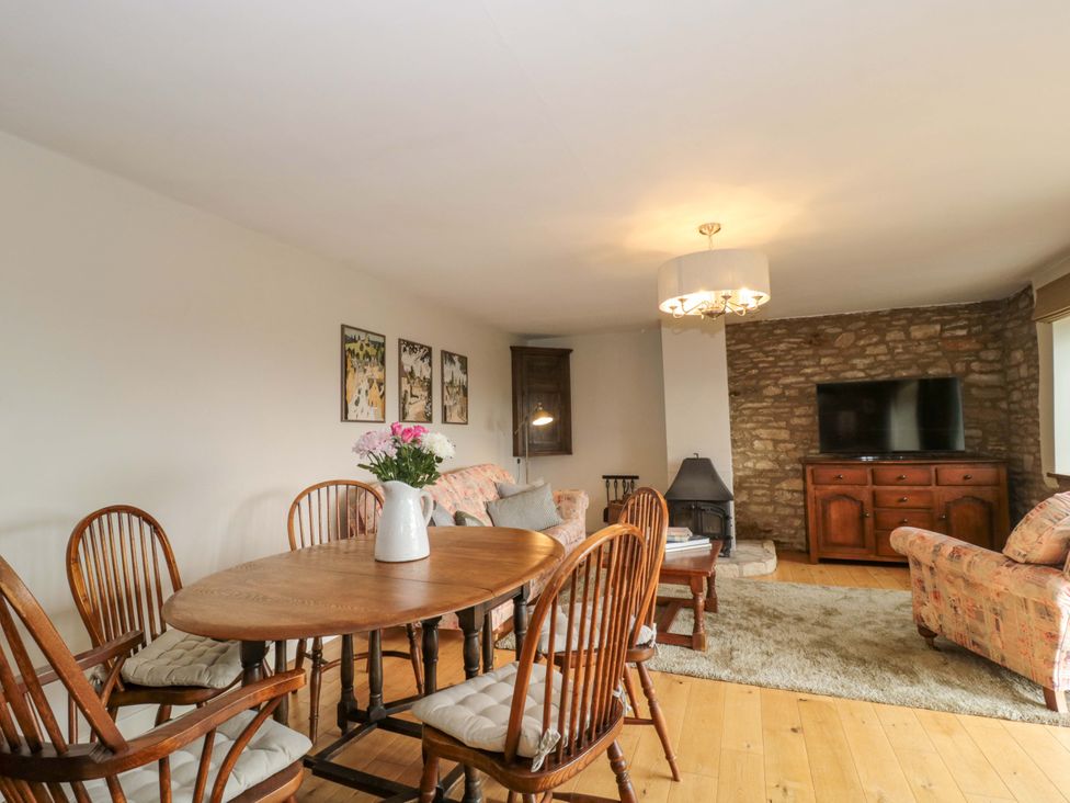A dining room with a table and chairs and a television cabinet at Daisy Bank in Maugersbury near Stow-On-The-Wold