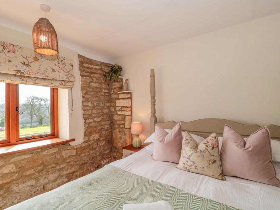 A bedroom with a bed and window at Daisy Bank in Maugersbury near Stow-On-The-Wold