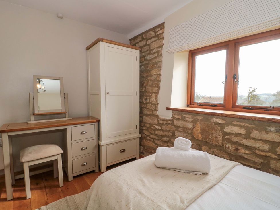 A bedroom with a bed and a wardrobe at Daisy Bank in Maugersbury near Stow-On-The-Wold