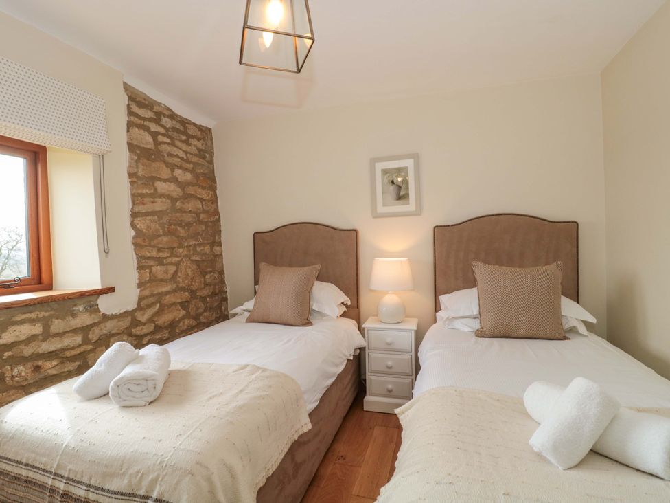 A bedroom with two beds and a window at Daisy Bank in Maugersbury near Stow-On-The-Wold