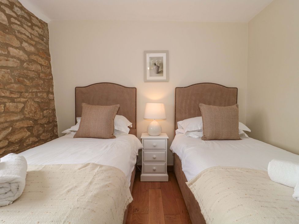 A bedroom with two beds and a nightstand at Daisy Bank Maugersbury near Stow-On-The-Wold