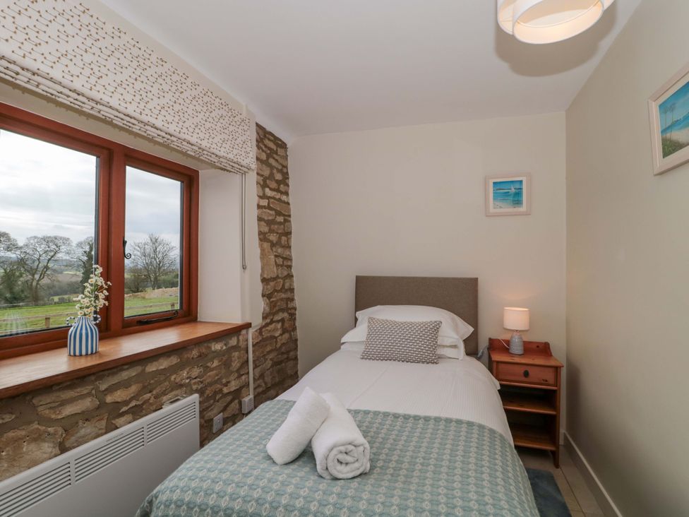 A bedroom with a bed and window at Daisy Bank in Maugersbury near Stow-On-The-Wold