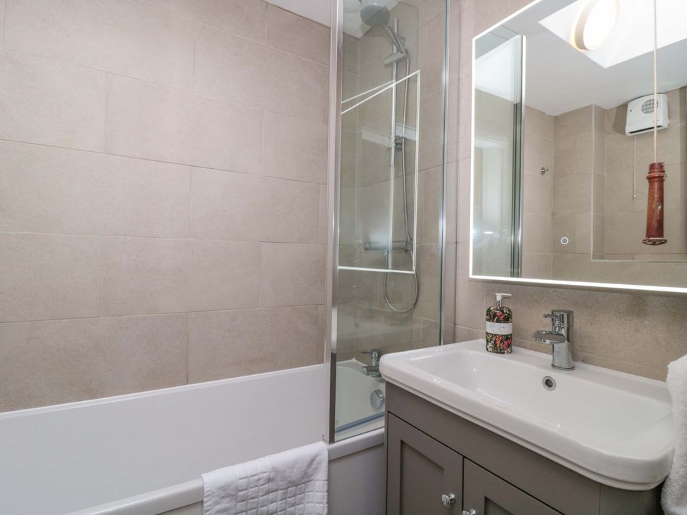 A bathroom with a bathtub, shower, and sink at Daisy Bank in Maugersbury near Stow-On-The-Wold