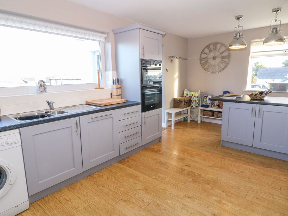 A kitchen with a sink, countertop, oven, and washing machine at Dunholme
