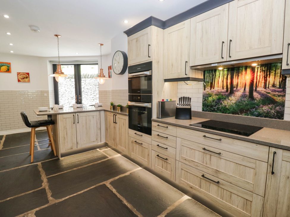A kitchen with wooden cabinets and a cooktop at Cragg Cottage in Coniston