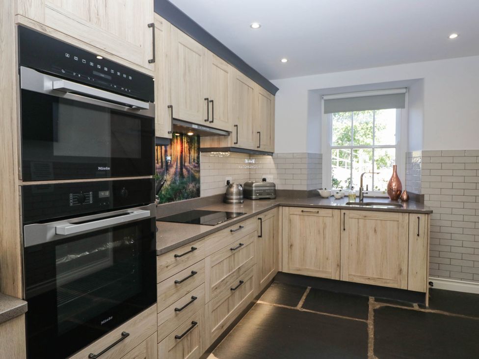 A kitchen with appliances and a window at Cragg Cottage in Coniston