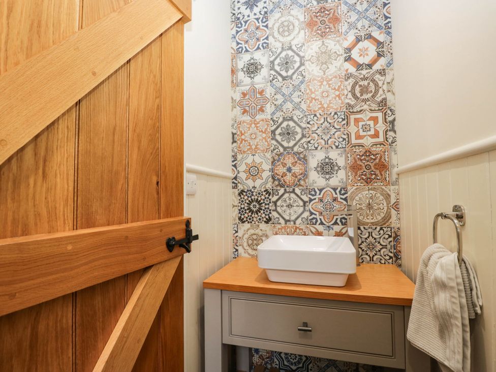 A bathroom with a sink and decorative wall tiles at Cragg Cottage in Coniston