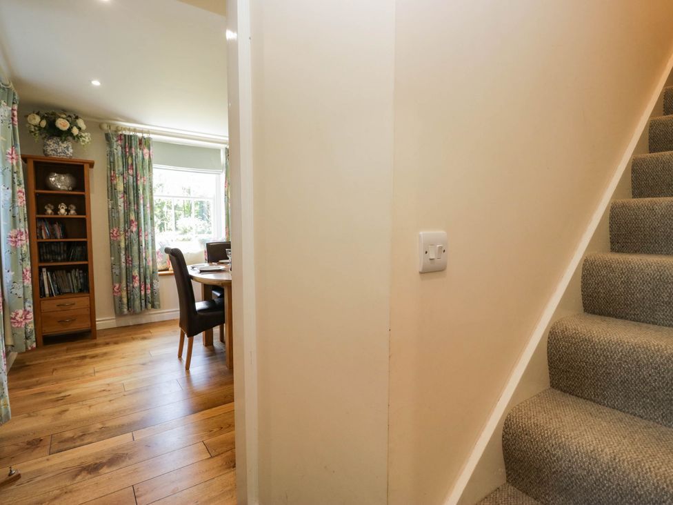 A dining room with a staircase and light switch at Cragg Cottage in Coniston