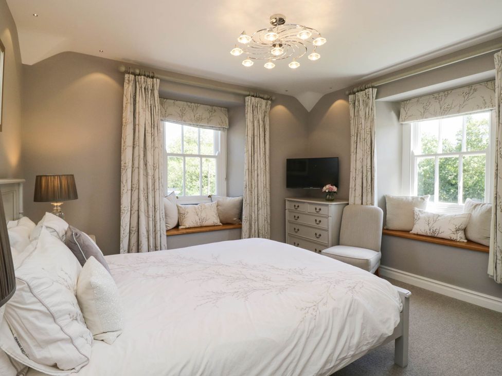 A bedroom with a bed, nightstand, and window seats at Cragg Cottage in Coniston