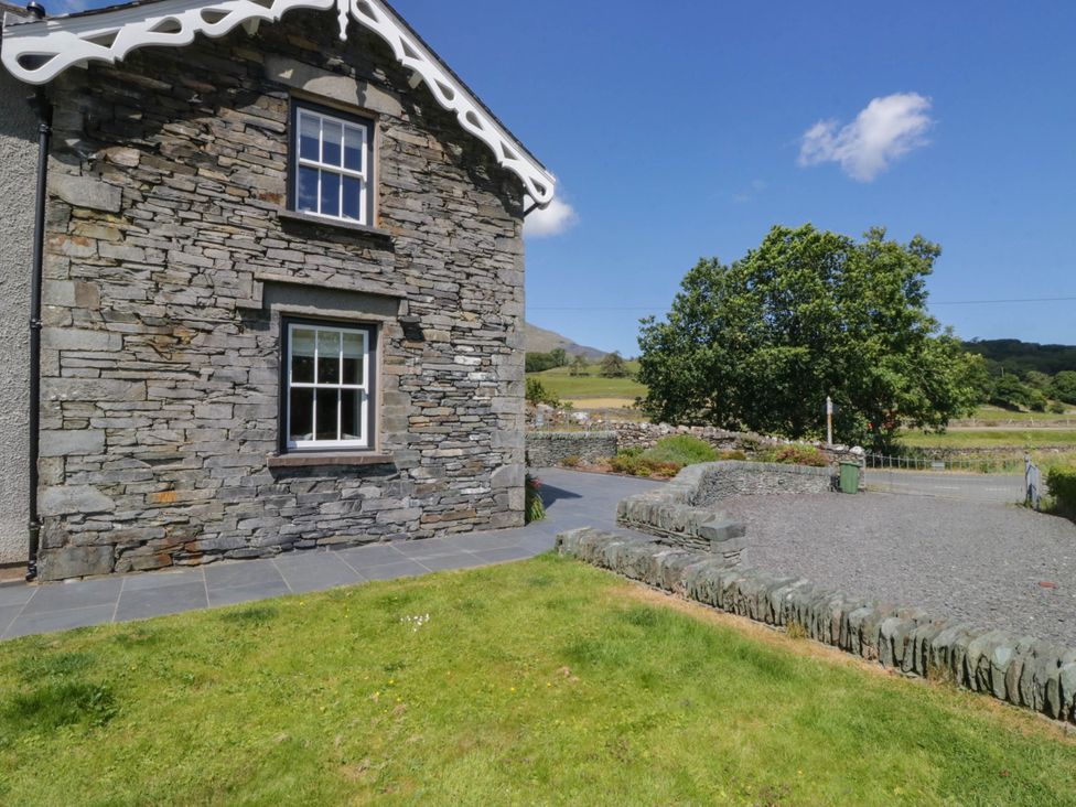 An outdoor view of a stone house with a window at Cragg Cottage in Coniston