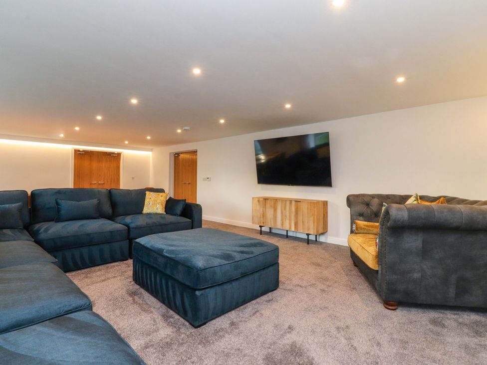 A living room with a sectional sofa and television at The Barn in Skipton