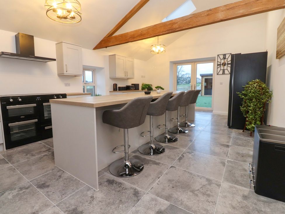 A kitchen with stools and an island at The Barn in Skipton