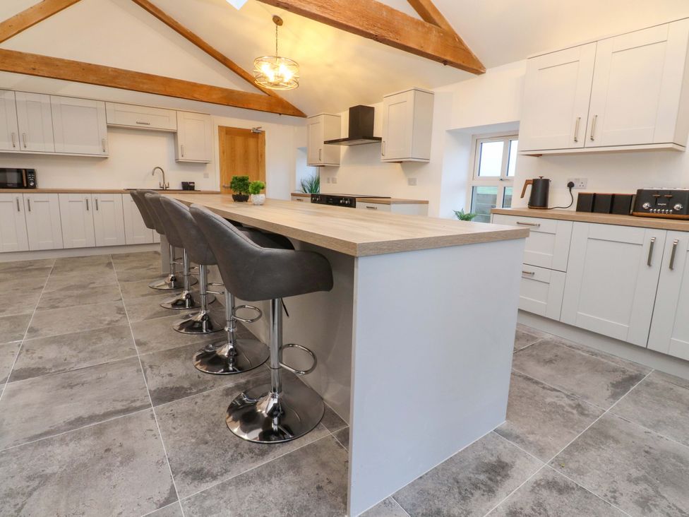 A kitchen with bar stools and kitchen appliances at The Barn in Skipton