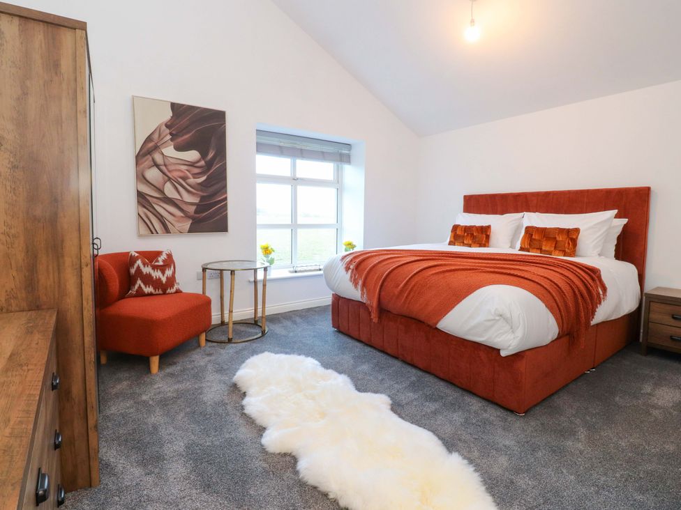 A bedroom with a bed and chair at The Barn in Skipton