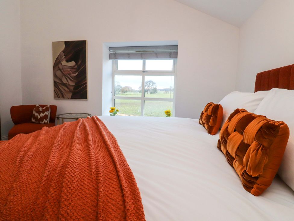 A bedroom with a bed and armchair at The Barn in Skipton