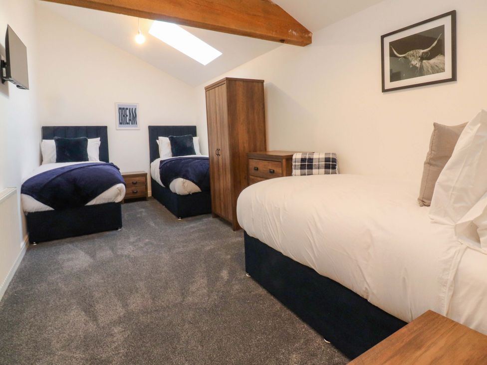 A bedroom with two beds and a wardrobe at The Barn in Skipton