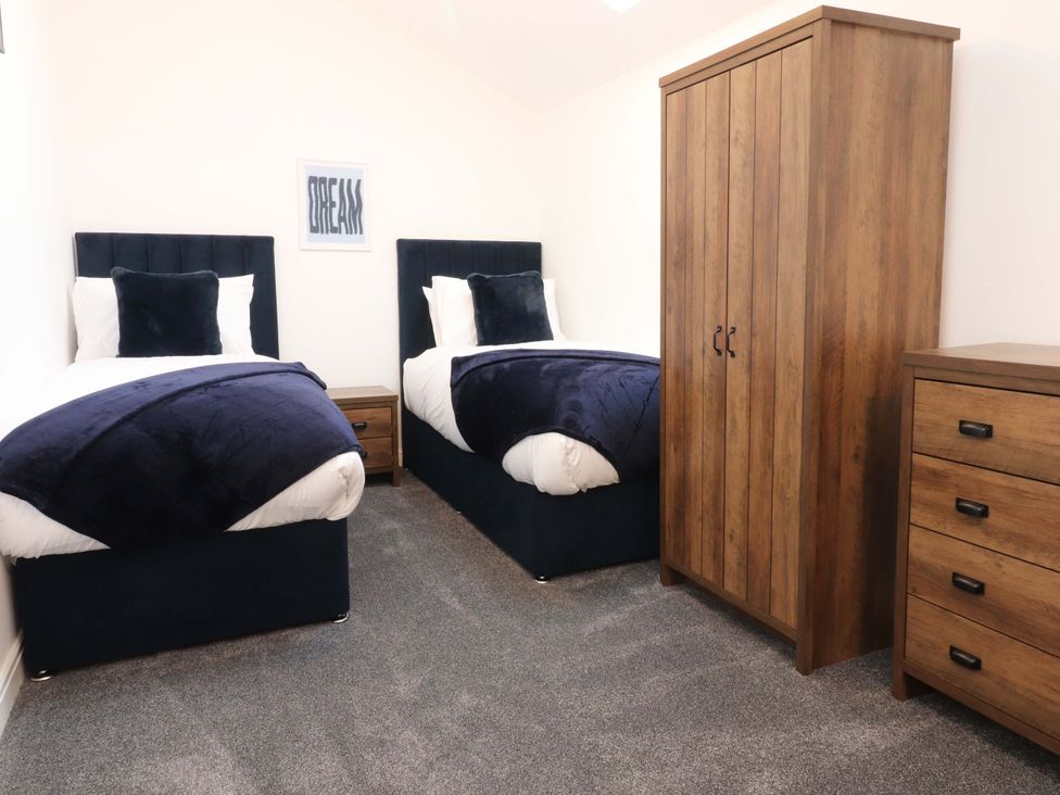 A bedroom with two beds and furniture including a wardrobe and chest of drawers at The Barn in Skipton