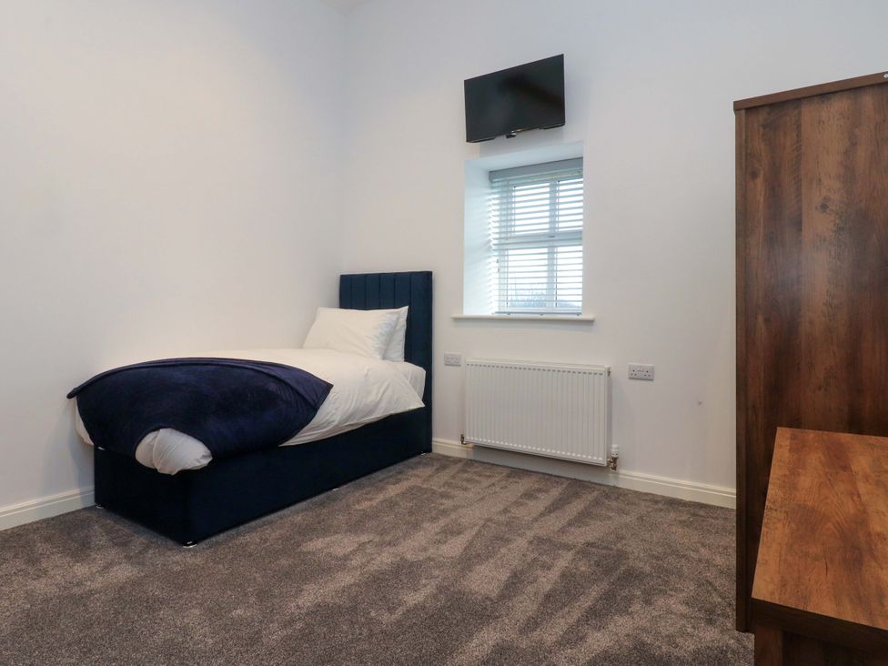A bedroom with a single bed and television at The Barn in Skipton