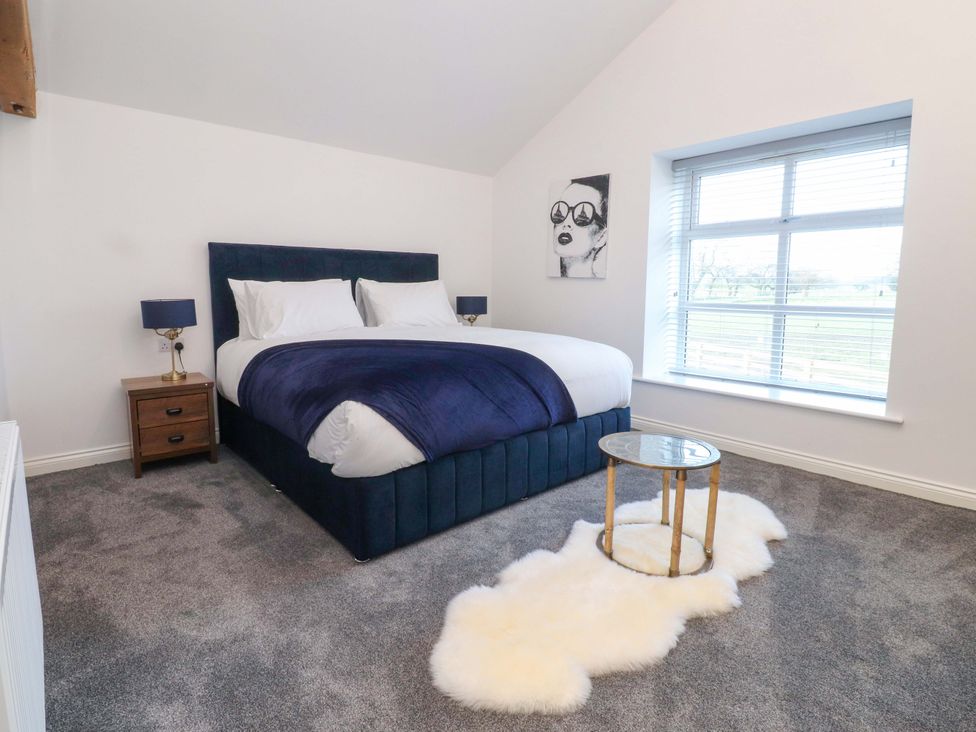 A bedroom with a bed, nightstand and window at The Barn in Skipton