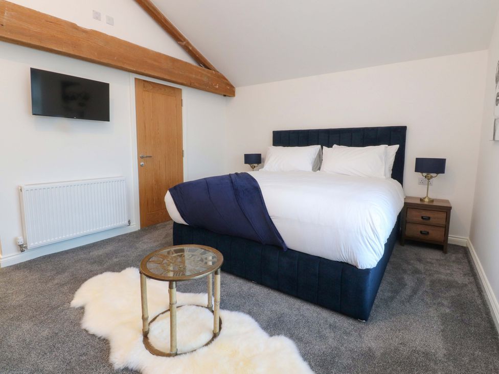 A bedroom with a bed and television at The Barn in Skipton
