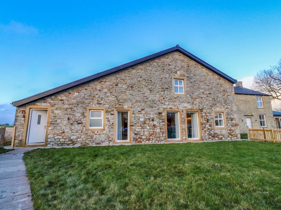 An exterior view of a stone house with windows and a door at The Barn in Skipton