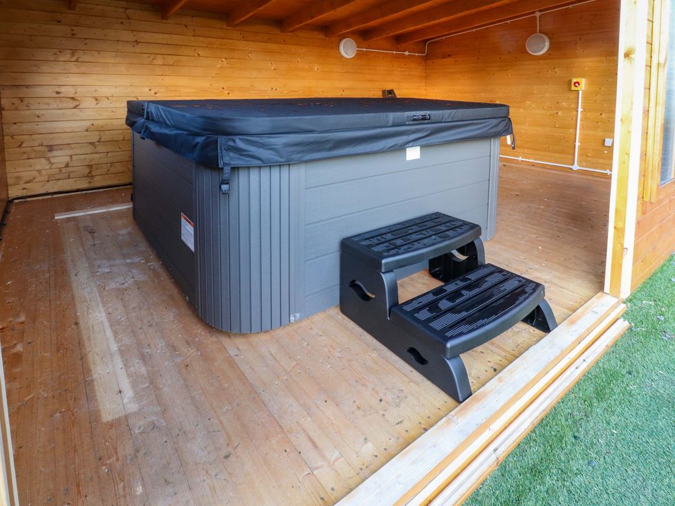 A hot tub with steps in a wooden interior at The Barn in Skipton