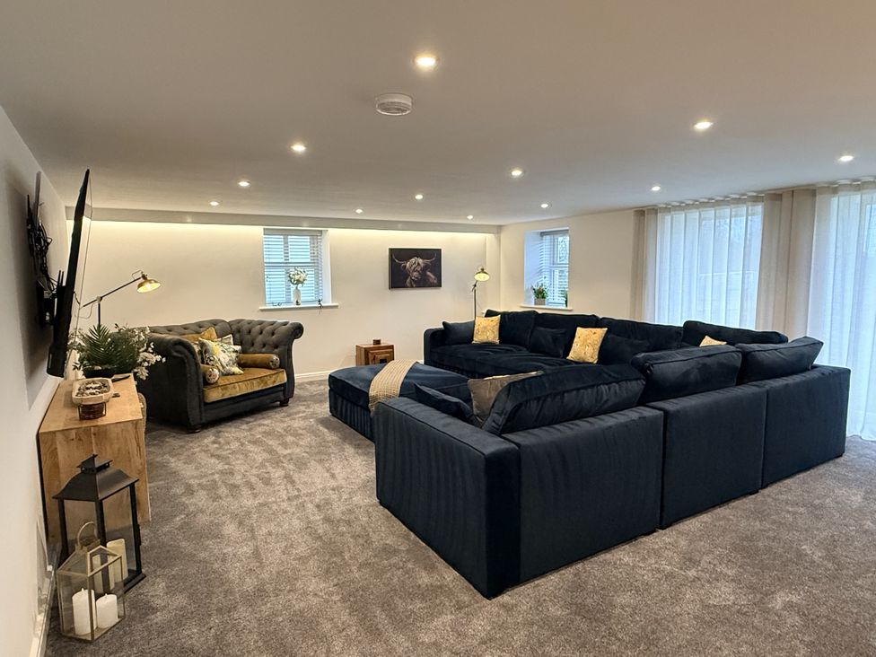 A living room with a large sofa and armchair at The Barn in Wigglesworth near Settle