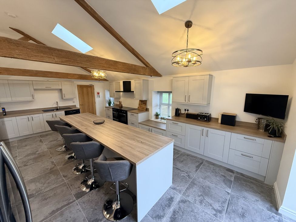 A kitchen with an island and bar stools at The Barn in Wigglesworth near Settle