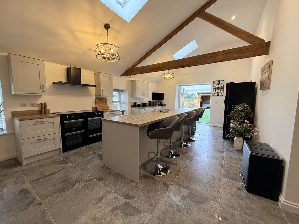 A kitchen with an island and bar stools at The Barn in Wigglesworth near Settle