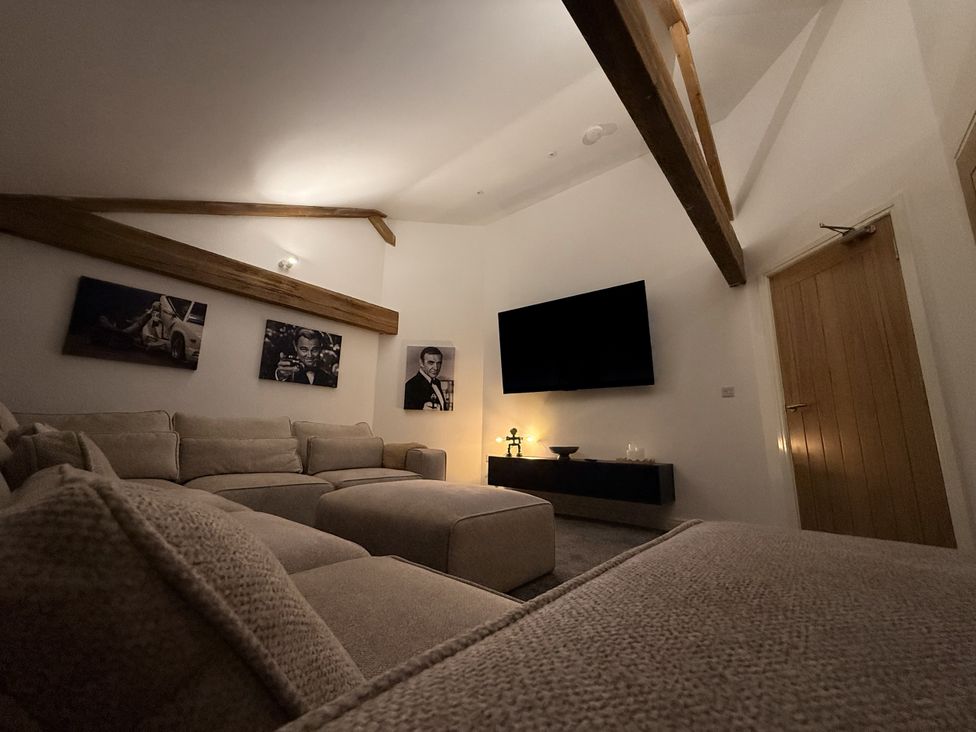 A living room with a large sofa and wall-mounted television at The Barn in Wigglesworth near Settle