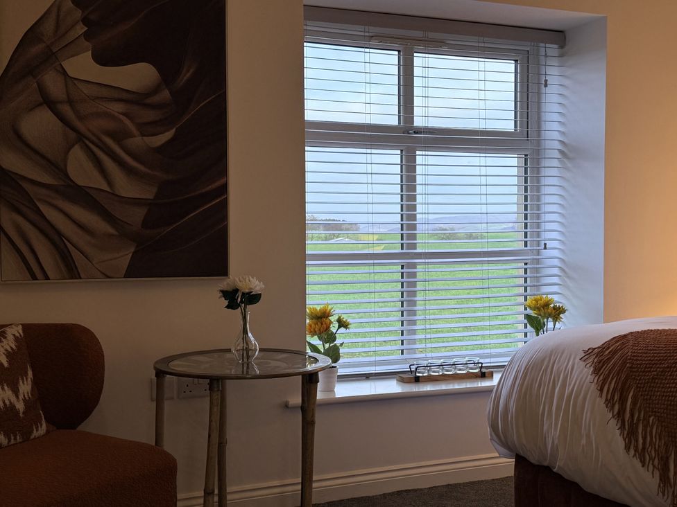 A bedroom with a window and flowers on a table at The Barn in Wigglesworth near Settle