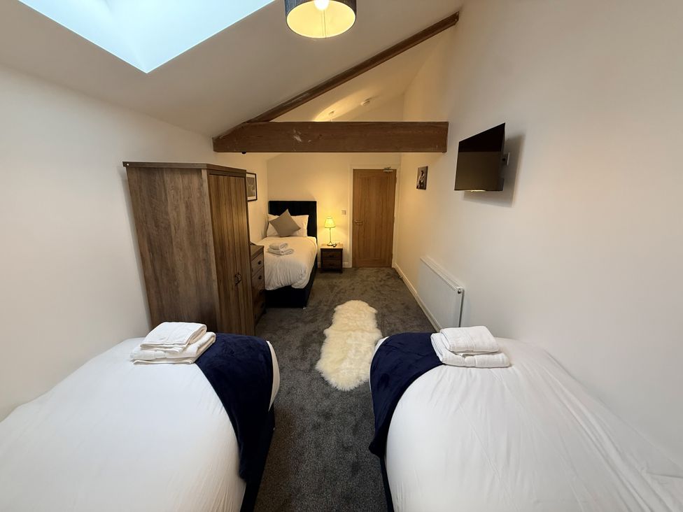 A bedroom with two beds and a wardrobe at The Barn in Wigglesworth near Settle