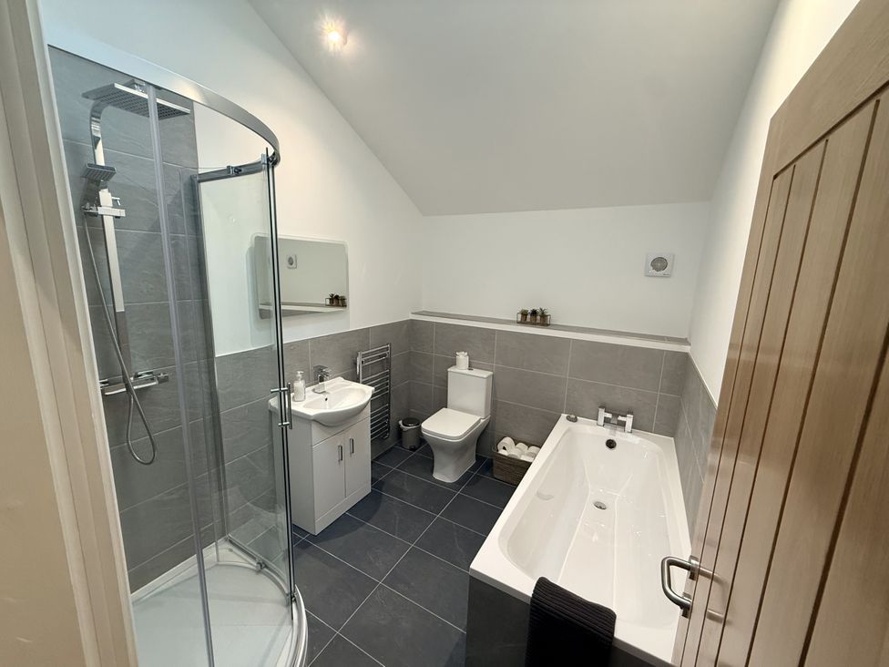 A bathroom with a bathtub, shower, toilet, and sink at The Barn in Wigglesworth near Settle