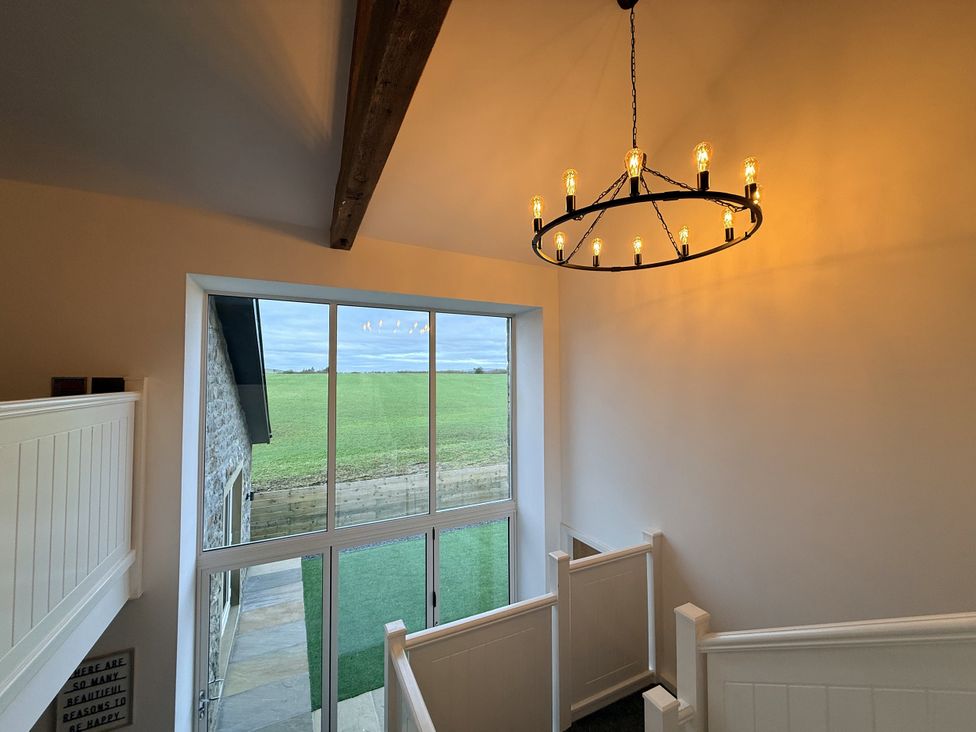 A staircase with a chandelier and windows at The Barn in Wigglesworth near Settle