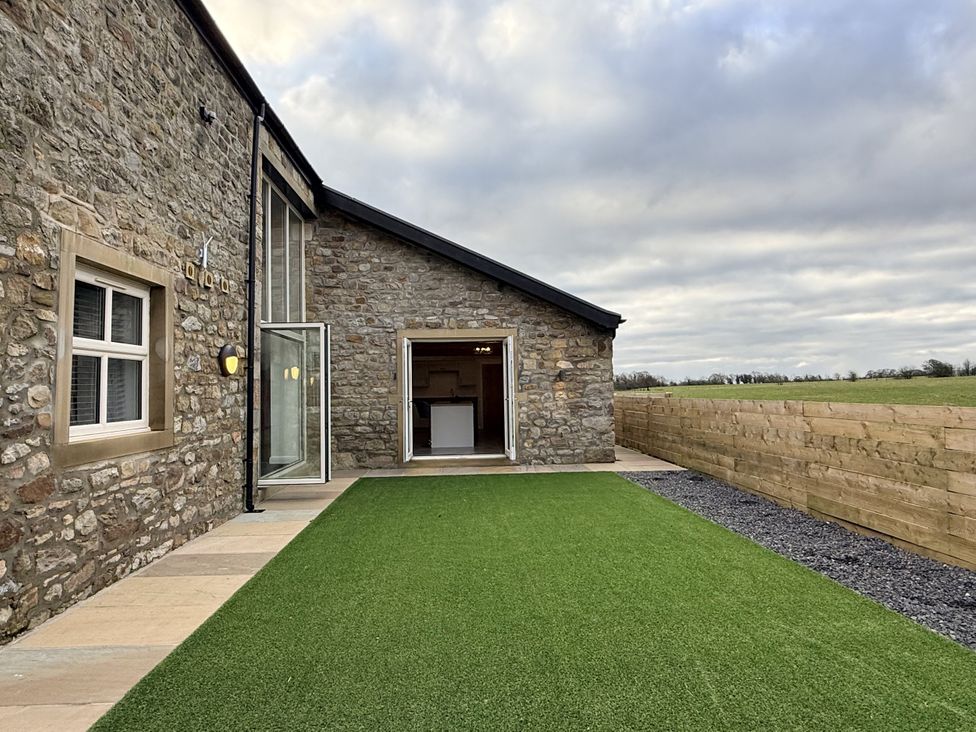 An outdoor area with a stone wall and grass at The Barn near Settle
