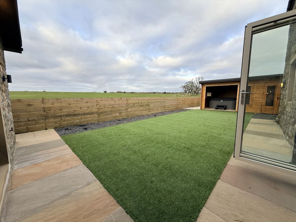 A garden with grass and a hot tub at The Barn in Wigglesworth near Settle