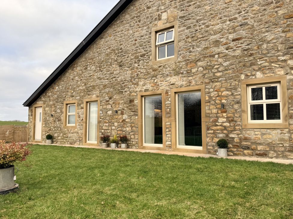 An exterior view of a stone house with windows and planters at The Barn in Wigglesworth near Settle