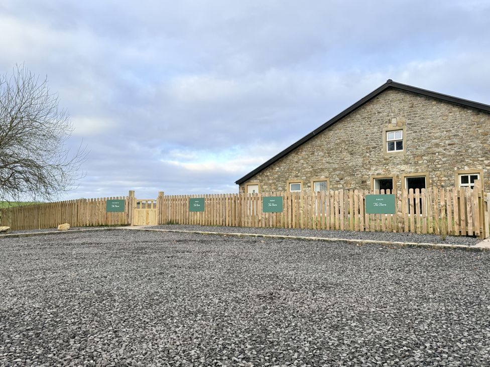 An outdoor area with a stone building and wooden fence at The Barn in Wigglesworth near Settle