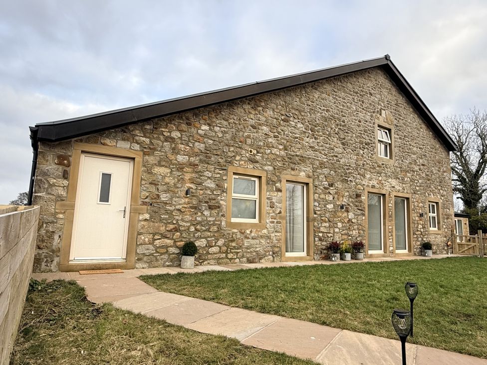A stone building with windows and a door surrounded by grass at The Barn in Wigglesworth near Settle