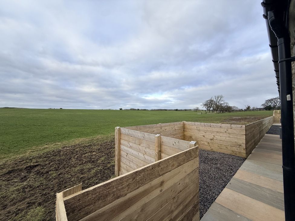 An outdoor area with wooden fencing and a grassy field at The Barn in Wigglesworth near Settle