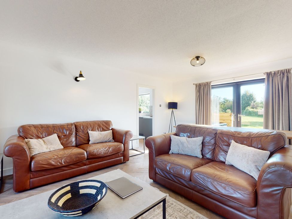 A living room with two leather sofas and a table at Low Greenlands House in Tewitfield