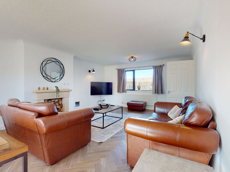 A living room with a sofa and television at Low Greenlands House in Tewitfield