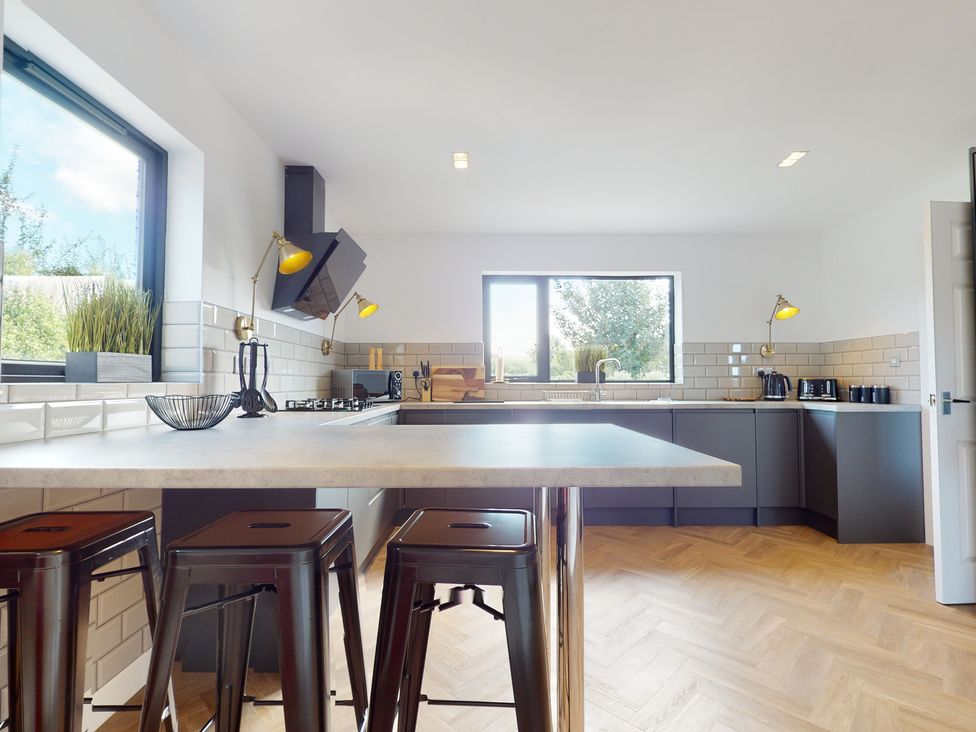A kitchen featuring cabinets, a sink, and stools at Low Greenlands House in Tewitfield