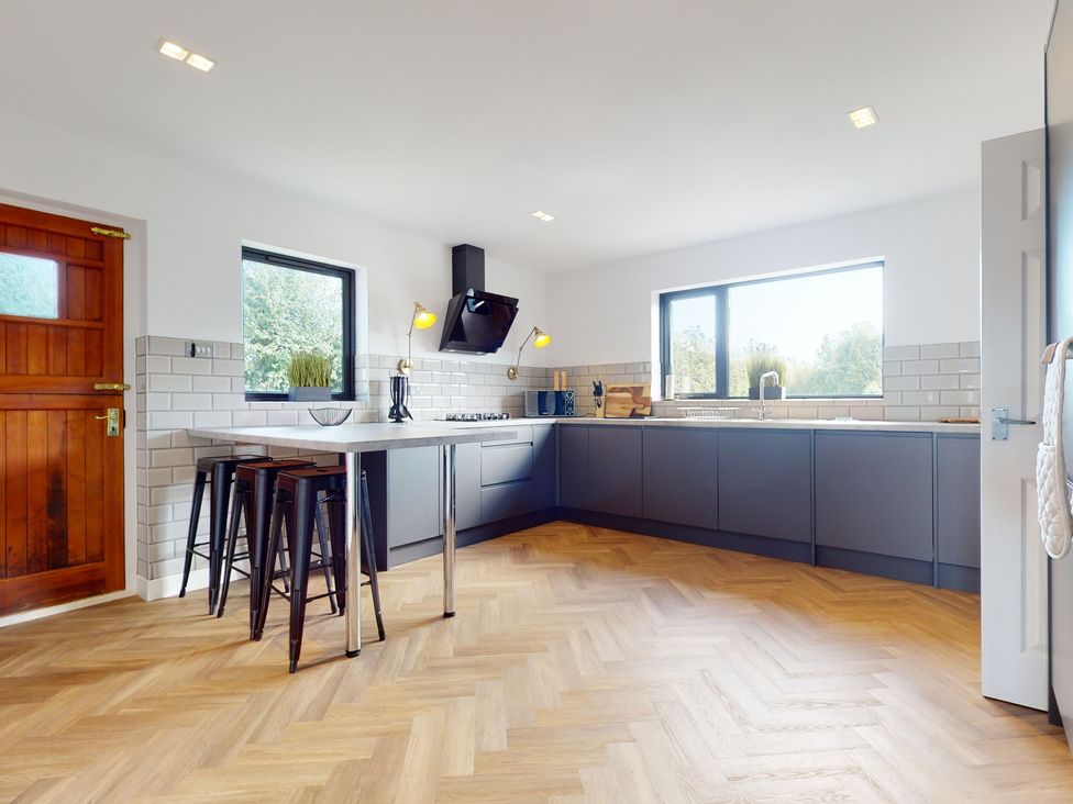 A kitchen with an island and stools at Low Greenlands House Tewitfield