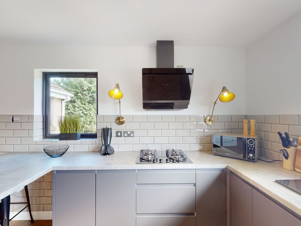 A kitchen with a gas stove and microwave at Low Greenlands House Tewitfield