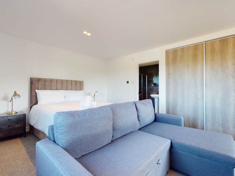 A bedroom with a bed, sofa, and wardrobe at Low Greenlands House in Tewitfield