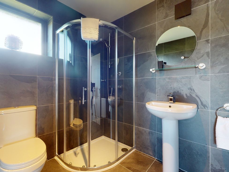 A bathroom with a shower, sink, and toilet at Low Greenlands House in Tewitfield