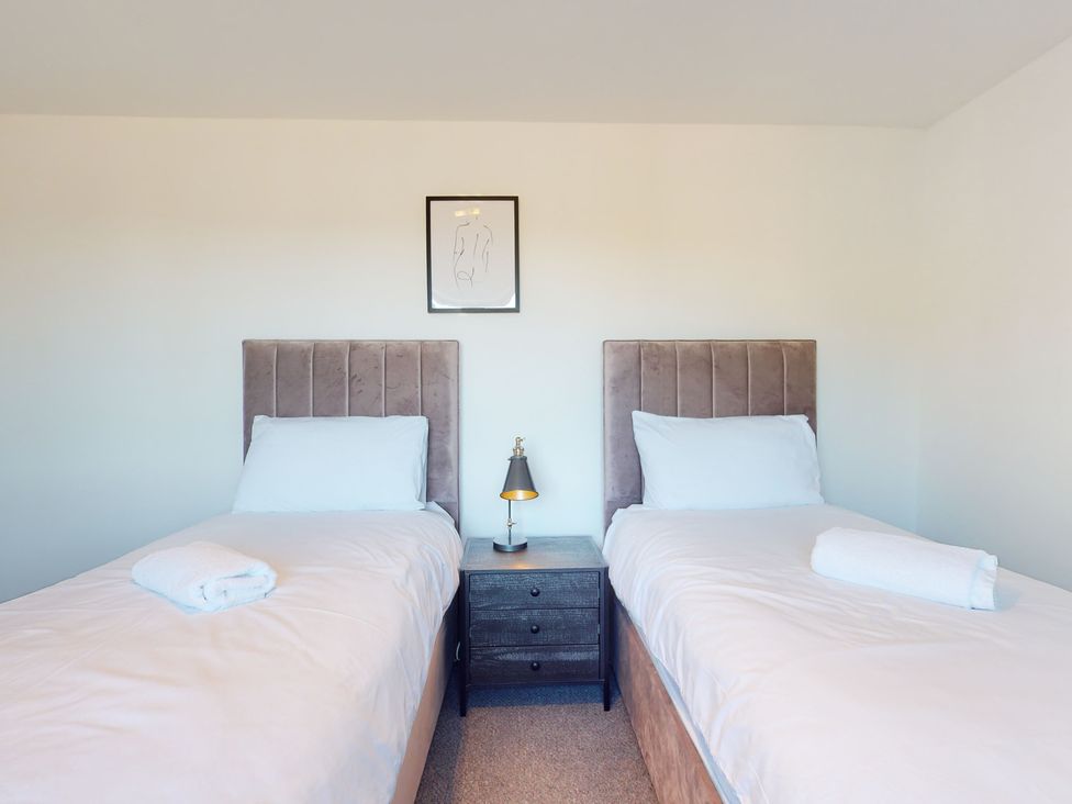 A bedroom with two single beds and a nightstand at Low Greenlands House in Tewitfield