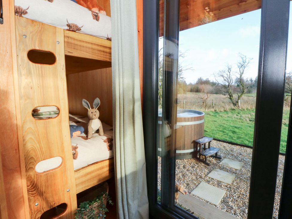 A bunk bed with a stuffed bunny and a view of a hot tub at Harriet in Llangurig